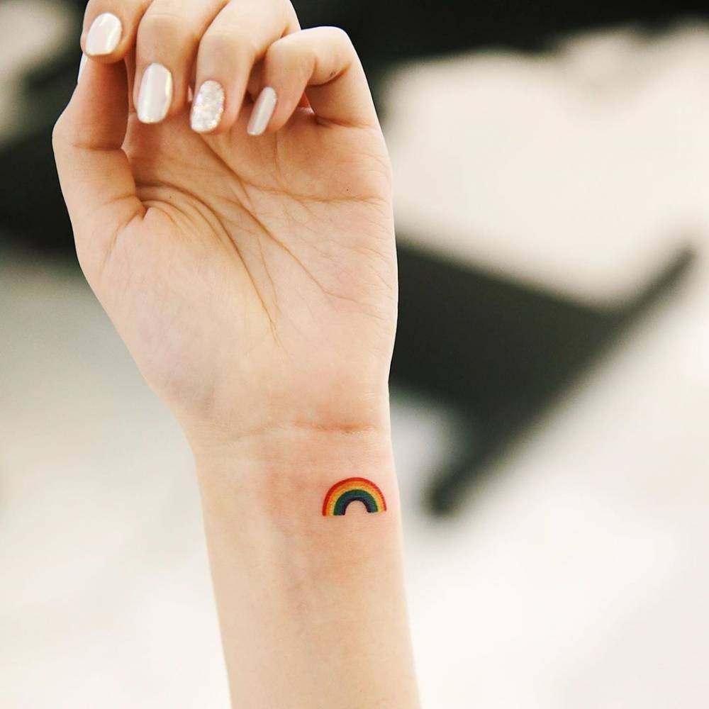 Hand poked rainbow tattoo on the right hand cloud